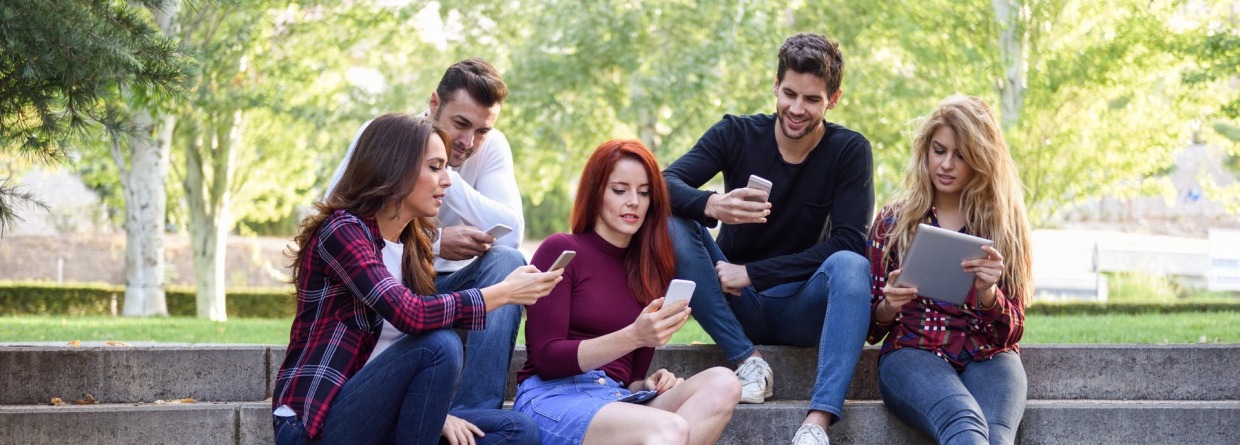 Studenten die op de trap zitten en naar hun mobiel kijken