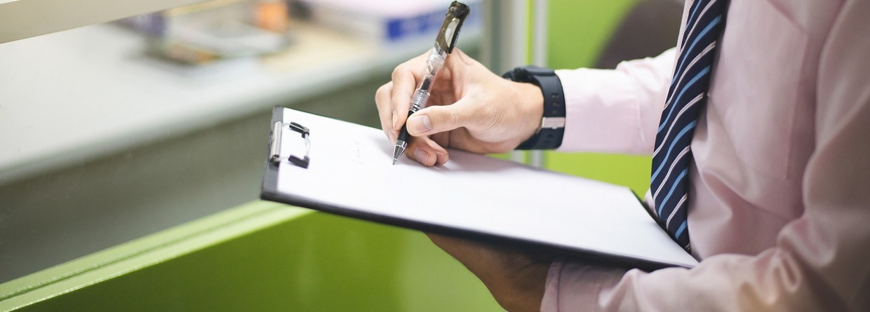 Medewerker van het bedrijf heeft een clipbord in zijn handen en maakt aantekeningen