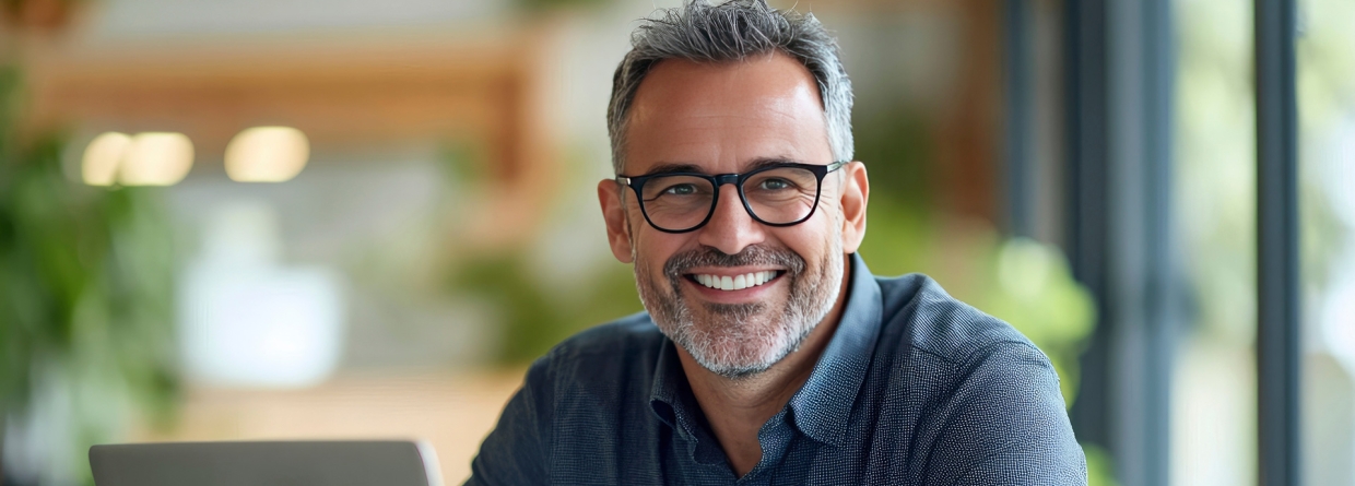 Een glimlachende, volwassen ondernemer met bril en overhemd