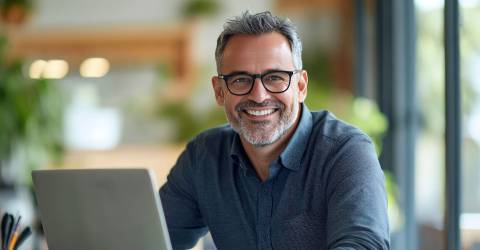 Een glimlachende, volwassen ondernemer met bril en overhemd